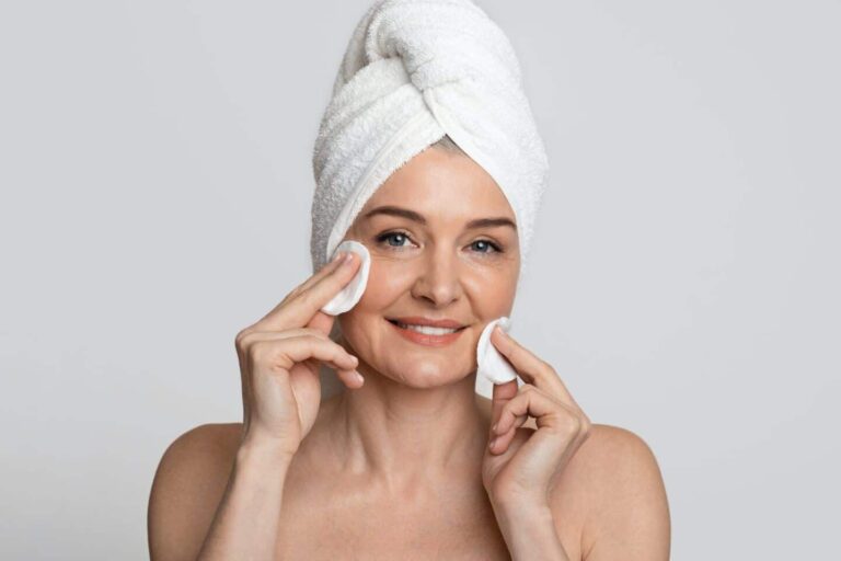Hermosa mujer de mediana edad limpiando su cara con tóner y almohadillas de algodón