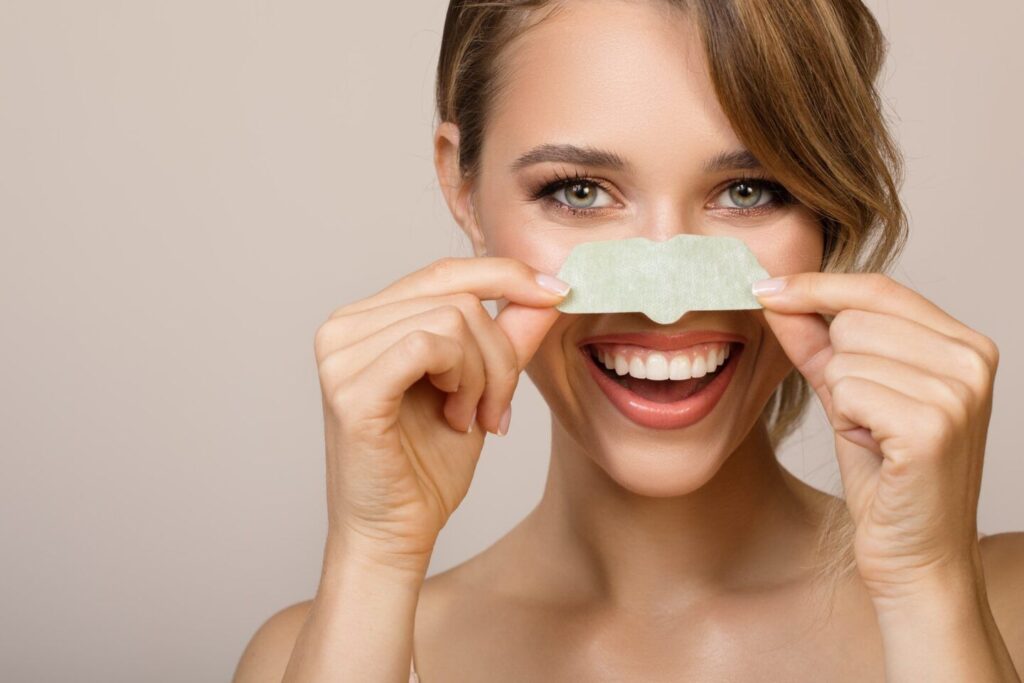 Mulher feliz usando máscara aplicadora de nariz contra poros dilatados